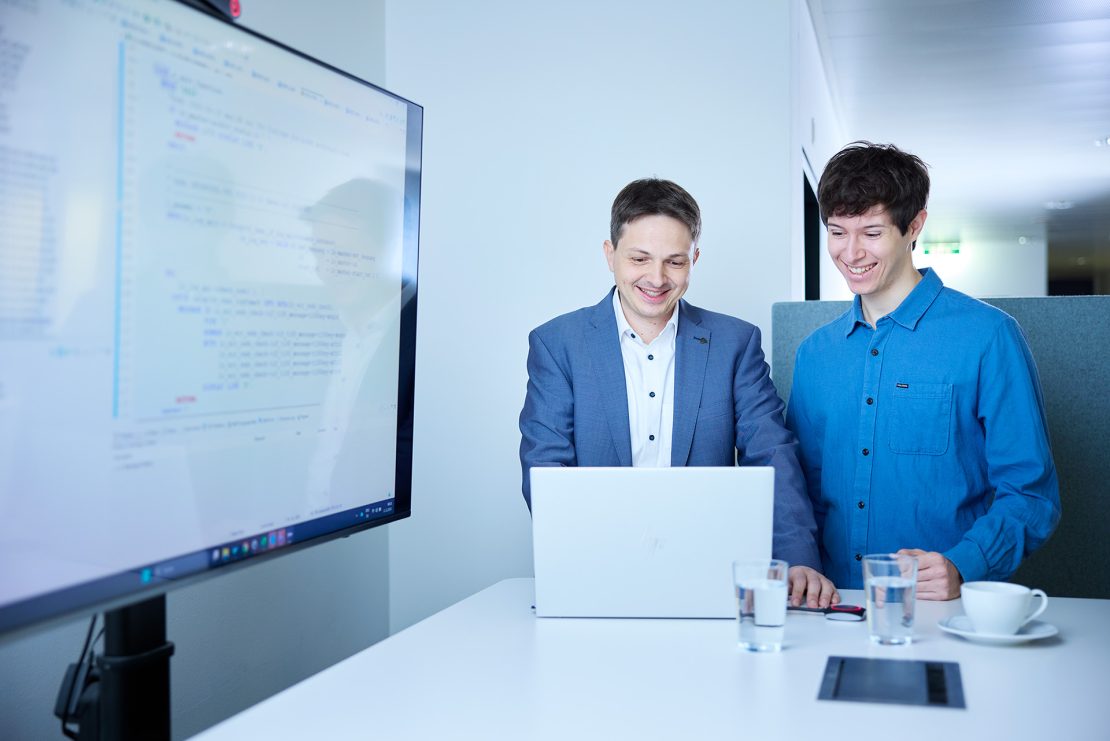 Software Developer der ATSP GmbH am Stehtisch mit großem Monitor und Laptop